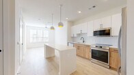 Located at 1610 N St Marys St in San Antonio, TX, this thoughtfully designed one-bedroom, one-bathroom residence offers a clean, modern aesthetic across its single floor. The open-concept layout seamlessly connects the kitchen and living area, creating an airy and functional living space bathed in natural light from large windows with blinds.

The kitchen is a standout feature, showcasing a two-tone design with crisp white upper cabinets and warm natural wood lower cabinets, all accented by matte black hardware. A large white waterfall-edge island serves as both a prep space and casual gathering spot, illuminated by stylish globe pendant lights with gold interiors. Stainless steel appliances, including a refrigerator, range, microwave, and dishwasher, complete the space alongside a sleek matte black faucet and white tile backsplash.

The bedroom offers a calm retreat with plush carpet flooring, a ceiling fan, and natural light. It includes access to a walk-in closet with built-in shelving. The bathroom features a floating white vanity, a large framed mirror, matte black fixtures, and light wood-tone flooring. Light wood floors run throughout the main living areas, tying the home's contemporary design together cohesively.