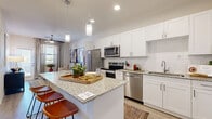 Located in Mesa, AZ, this thoughtfully designed one-bedroom, one-bathroom residence offers a well-appointed single-floor layout that maximizes both comfort and functionality. The open-concept kitchen is a standout feature, showcasing crisp white shaker cabinetry, a white subway tile backsplash, granite countertops, stainless steel appliances, and a central island with pendant lighting and bar seating — ideal for casual dining or entertaining. Light wood-tone flooring flows consistently throughout, enhancing the bright, airy atmosphere created by recessed lighting and natural light from well-placed windows. The living room is an inviting retreat, featuring a ceiling fan, a sliding glass door that welcomes natural light, and enough space for comfortable seating arrangements. In-unit laundry is conveniently located just off the kitchen. The bedroom offers a serene environment with a ceiling fan, natural light from a large window, and direct access to the bathroom. The bathroom is elegantly finished with granite countertops, white cabinetry, a large mirror, and a soaking tub with tiled surround. The dedicated walk-in closet provides generous storage with multiple hanging rods and built-in shelving, completing this well-rounded and stylishly finished residence.
