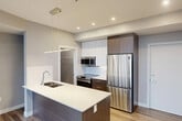 Located at 11450 80 Ave NW in Edmonton's desirable South Side neighborhood, this modern 2-bedroom, 2-bathroom unit offers a thoughtfully designed open-concept layout with contemporary finishes throughout. Wide-plank wood-style flooring flows seamlessly across the main living areas, complementing the neutral grey tones and clean lines that define the space.

The kitchen serves as a central hub, anchored by a generous island with a double undermount sink, white quartz countertops, and dark wood cabinetry. Stainless steel appliances — including a French door refrigerator, electric range, built-in microwave, and dishwasher — complete the chef-friendly setup. Pendant lighting above the island adds a refined touch, while open wire shelving provides additional pantry storage.

The living area benefits from large windows that draw in natural light and frame views of the surrounding neighborhood. The primary bedroom features a sliding glass door with outdoor views and a dedicated closet with wire shelving. Both bathrooms are finished with marble-look tile surrounds and sliding glass doors — one with a soaker tub and the other with a stand-up shower. Three closets and an in-suite laundry room provide practical storage throughout. The hallway connects all rooms with a clean, efficient flow.