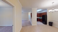 This single-floor residence offers a thoughtfully designed open-concept layout that seamlessly connects the main living areas. The kitchen is a functional highlight, featuring rich cherry wood cabinetry, granite countertops, black appliances including a refrigerator and range with an overhead vent hood, and tile flooring. A decorative column defines the transition between the kitchen and the adjoining dining area, which is accented by an elegant chandelier and crown molding.

The living room is generously proportioned, with soft carpeting, crown molding, a ceiling fan with light fixture, and French doors that invite natural light and provide outdoor access. The neutral color palette throughout creates a bright, welcoming ambiance.

The bedrooms are carpeted and well-sized, with large windows offering natural light. At least one bedroom features a walk-in closet with built-in shelving. The bathrooms are finished with granite-topped cherry vanities and tile flooring. One bathroom is equipped with accessibility grab bars near the toilet and shower area, reflecting inclusive design. Crown molding and consistent trim details are found throughout, lending a polished, cohesive aesthetic to the entire space.