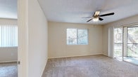 This single-floor residence offers a functional and comfortable layout with a cohesive neutral color palette throughout. The spacious living area is fitted with plush carpet flooring, a ceiling fan with integrated lighting, and direct access to a private balcony through a sliding glass door, framed by views of mature trees that bring a sense of natural calm to the interior. A large window further enhances the flow of natural light into the space.

The kitchen is well-equipped and features granite-style countertops, white cabinetry, a stainless steel built-in microwave, a dishwasher, and an electric range — all set atop warm hardwood-style flooring. A breakfast bar connects the kitchen to the main living area, creating an open and social atmosphere.

The bedrooms are carpeted and generously sized, each benefiting from windows with outdoor tree views and ceiling fans to maintain comfort. The rooms are bright and versatile, suitable for a variety of living arrangements.

The bathrooms feature granite-style vanity countertops, white cabinetry, hardwood-style flooring, and tub-shower combinations, maintaining a clean and consistent design aesthetic. A hallway with panel doors provides access to closet storage and connects the private areas of the home seamlessly. Textured ceilings are present throughout, adding a classic residential character to the space.