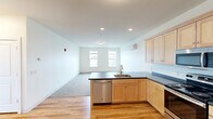 Located at 268 E Allen St, Unit 410 in Winooski, Vermont, this well-designed 3-bedroom, 1-bathroom unit offers a practical and comfortable layout across a single floor. The open-concept kitchen and living area serves as the heart of the unit, featuring warm light maple cabinetry, dark countertops, and a full suite of stainless steel appliances including a refrigerator, range, microwave, and dishwasher. Hardwood flooring runs throughout the kitchen and entry areas, while plush carpeting provides comfort in the bedrooms and living space. The entry foyer includes a built-in coat hook rail, offering a welcoming and organized arrival point. Each of the three bedrooms is bright and generously sized, with large windows that invite natural light and offer views of the surrounding Winooski landscape and skyline. The spacious primary bedroom features a double-door closet and an additional window with scenic outdoor views. A dedicated closet provides wire shelving and hanging space for ample storage. The bathroom is clean and functional, with a full tub-shower combo, wood-toned vanity, and hardwood flooring. Individual wall-mounted mini-split units provide climate control in the bedrooms, complemented by baseboard heating throughout.
