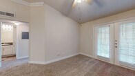 This single-story residence at 10901 Ranchstone Dr in Houston, Texas offers a thoughtfully designed layout with a variety of notable architectural and interior features. The living areas are distinguished by vaulted ceilings with ceiling fans, lending a sense of openness and airflow throughout the space. Plush carpeting covers the floors in the main living and bedroom areas, while wood-look flooring is found in the kitchen and bathroom, providing a practical contrast.

The living area features French doors with blinds that allow natural light to filter in while offering a view of the outdoors. Additional rooms include spaces with large windows dressed with horizontal blinds, further enhancing natural light and providing greenery views.

The kitchen is well-appointed with white shaker-style cabinetry, dark granite countertops, a subway tile backsplash, and stainless steel appliances including a range and over-the-range microwave. The bathroom mirrors the kitchen's design with matching white cabinetry, dark granite countertops, and a tub-shower combination. Crown molding accents select rooms, adding a refined finishing touch. The overall color palette of warm neutral tones creates a clean, cohesive ambiance throughout.