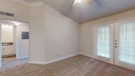 This single-story residence at 10901 Ranchstone Dr in Houston, Texas offers a thoughtfully designed layout with a variety of notable architectural and interior features. The living areas are distinguished by vaulted ceilings with ceiling fans, lending a sense of openness and airflow throughout the space. Plush carpeting covers the floors in the main living and bedroom areas, while wood-look flooring is found in the kitchen and bathroom, providing a practical contrast.

The living area features French doors with blinds that allow natural light to filter in while offering a view of the outdoors. Additional rooms include spaces with large windows dressed with horizontal blinds, further enhancing natural light and providing greenery views.

The kitchen is well-appointed with white shaker-style cabinetry, dark granite countertops, a subway tile backsplash, and stainless steel appliances including a range and over-the-range microwave. The bathroom mirrors the kitchen's design with matching white cabinetry, dark granite countertops, and a tub-shower combination. Crown molding accents select rooms, adding a refined finishing touch. The overall color palette of warm neutral tones creates a clean, cohesive ambiance throughout.