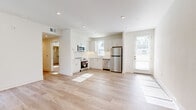This well-designed single-floor residence offers a clean, modern aesthetic throughout, characterized by crisp white walls, recessed lighting, and an abundance of natural light. The open living area greets visitors with light-toned hardwood flooring and a striking navy pivot door that opens to an outdoor space, framing views of lush greenery. Windows fitted with horizontal blinds allow for adjustable natural light across the main living spaces.

The kitchen is thoughtfully appointed with white shaker cabinetry, a classic white subway tile backsplash, and a full suite of stainless steel appliances, including a refrigerator, range, microwave, and dishwasher. Light wood flooring continues seamlessly from the living area into the kitchen, reinforcing the open, airy feel of the shared spaces.

The bedrooms offer a comfortable retreat, with some featuring warm neutral carpet and others continuing the light hardwood flooring. Each room includes windows with exterior views and ample wall space for flexible arrangement.

The bathroom is a standout feature, showcasing bold geometric hexagonal floor tile in a black-and-white pattern, paired with a white vanity, clean countertops, and a well-lit mirror. The overall design of this residence balances contemporary finishes with a welcoming, functional layout.