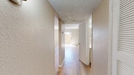 This two-story residence offers a well-organized layout with distinct living areas spread across both levels. The main floor features durable wood-style flooring throughout, complemented by neutral-toned walls and textured ceilings. A ceiling fan in the living area enhances comfort, while a sliding glass door floods the space with natural light and provides direct access to a private fenced outdoor area. A staircase connects the two floors, adding to the functional flow of the home.

The galley-style kitchen is thoughtfully appointed with cream cabinetry, quartz-style countertops, a mosaic tile backsplash, a double-basin sink, and included appliances such as an electric range and refrigerator. A window above the counter brings in natural light.

Upstairs, the bedrooms feature plush carpeting and textured walls, with at least one room offering a ceiling fan and a window with exterior views. The bathrooms are finished with wood-look flooring, white vanities with marble-style countertops, and a full tub-shower combination. A half bath on the lower level provides added convenience for guests.

Throughout, the space maintains a clean, neutral palette with consistent finishes, creating a cohesive and functional living environment across both floors.