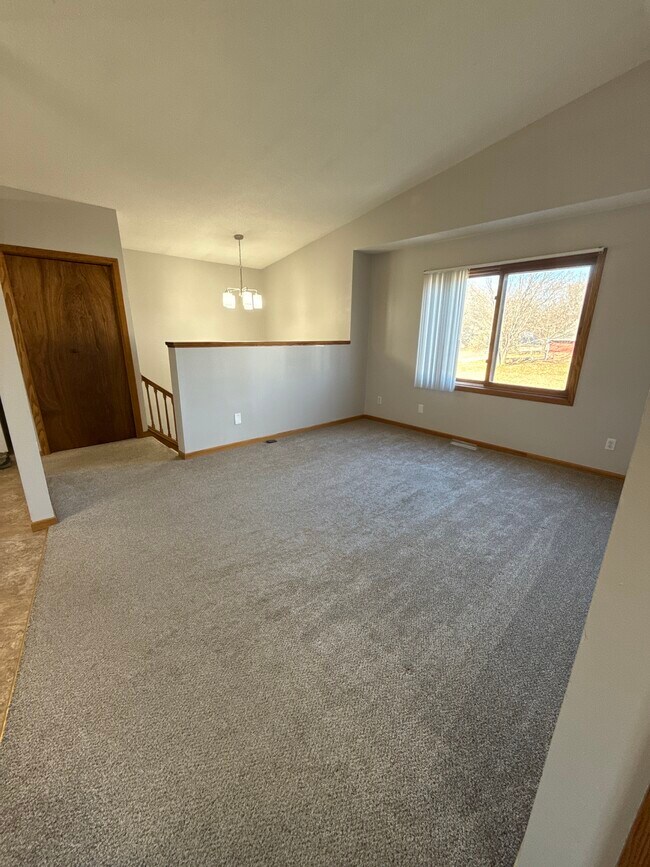 Amplio salón en la planta superior con techos abovedados y gran ventanal que permite la entrada de luz natural. - 9092 Goldenrod Ln N