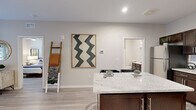 This single-story, one-bedroom, one-bathroom unit offers a thoughtfully designed layout that maximizes its comfortable footprint. Light wood-style flooring flows throughout, complementing the neutral, warm-toned walls that create a cohesive and inviting atmosphere.

The kitchen is a standout feature, equipped with rich dark-brown cabinetry, granite countertops, a white subway tile backsplash, and a full suite of stainless steel appliances including a refrigerator, range, microwave, and dishwasher. A granite-topped island provides additional prep space and casual seating. The kitchen opens directly into the living area, which benefits from large windows and glass doors that admit generous natural light and offer outdoor views. A ceiling fan adds both function and style to the living space.

The bedroom is a well-proportioned retreat featuring a ceiling fan, a large window with outdoor views, and easy access to a dedicated closet outfitted with wire shelving for organized storage.

The bathroom includes a full tub-shower combination, a dark-cabinetry vanity with granite countertops, and clean tile flooring, completing this efficiently designed and attractively finished unit.