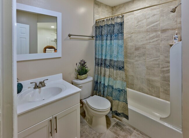 Disfrute de un baño limpio y moderno en Haynes Run Apartments con azulejos neutrales, accesorios elegantes y elementos de diseño actualizados. - Haynes Run