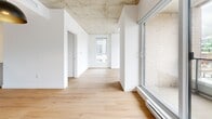 Located at 2198 Boulevard De Maisonneuve Est in Montréal, this well-designed 2-bedroom, 1-bathroom unit offers a contemporary urban living experience with thoughtful architectural details throughout. Warm light hardwood flooring runs continuously across the entire space, complemented by crisp white walls and striking exposed concrete ceilings that lend an industrial-modern character to every room.

The open-concept kitchen and living area form the heart of the unit. The kitchen features flat-front white cabinetry, a white quartz island with an undermount sink and integrated dishwasher, stainless steel appliances including a full-size refrigerator and gas range, and a classic subway tile backsplash. A bold pendant light anchors the dining area, while floor-to-ceiling windows and a sliding door to the balcony flood the living space with natural light and offer views of the surrounding neighbourhood.

Both bedrooms are bright and well-proportioned, each featuring large windows with urban views and exposed concrete ceiling details. The primary bedroom includes a closet with sliding doors. The full bathroom is finished with large-format neutral floor tiles, warm taupe wall tiles surrounding the soaker tub and shower, a floating vanity with undermount sink, and recessed lighting. An in-unit laundry area completes this functional and stylish urban home.