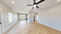This well-designed 2-bedroom, 1-bathroom unit offers a thoughtful layout across a single floor, combining modern finishes with a bright, welcoming atmosphere. Light wood-look flooring runs consistently throughout the space, creating a cohesive and clean aesthetic from room to room.

The open-concept living area is anchored by a sleek ceiling fan and recessed lighting, with natural light streaming in through multiple windows that offer views of the surrounding neighborhood. A glass-paneled exterior door further enhances the sense of openness and connectivity to the outdoors.

The kitchen is a standout feature, showcasing bold teal shaker-style cabinetry with matte black hardware, crisp white countertops, and a full suite of appliances including a refrigerator, range, and microwave. A window above the sink adds natural light to the workspace.

The primary bedroom is generously sized, accommodating a ceiling fan and multiple windows that invite abundant daylight and outdoor views. The second bedroom is equally well-lit with large windows and its own ceiling fan. A dedicated closet and hallway provide practical storage and circulation.

The bathroom is finished in a clean, modern style with teal cabinetry matching the kitchen, a white countertop vanity, a full tub/shower combo, and recessed lighting — completing this move-in-ready home.