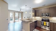 Located at 605 W Chapel Hill St in downtown Durham, NC, this single-floor residence offers a well-designed open layout with contemporary finishes throughout. The kitchen serves as a central focal point, featuring rich dark wood cabinetry, granite countertops, a peninsula island with an undermount sink, and a full suite of stainless steel appliances including a range, microwave, dishwasher, and refrigerator. Pendant lighting above the island adds a stylish, functional touch, while wood-style flooring runs throughout the main living areas. A breakfast bar with seating opens the kitchen seamlessly to the living area, which benefits from natural light and direct access to a private balcony through sliding glass doors. A ceiling fan enhances comfort in the living space. The bedroom features neutral carpet, a window with blinds, and a clean, versatile layout. The bathroom is outfitted with a tiled tub/shower combination, a granite-topped vanity with dark wood cabinetry, and tile flooring. A dedicated in-unit laundry closet houses a stacked washer and dryer, adding everyday convenience. The unit's neutral color palette and modern finishes create a cohesive, contemporary ambiance throughout.