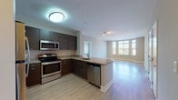 This single-floor residence is designed with a clean, contemporary aesthetic and a practical open-concept layout. The kitchen serves as a central feature, outfitted with dark espresso-toned cabinetry, granite countertops, and a full suite of stainless steel appliances including an electric range, built-in microwave, dishwasher, and refrigerator. A peninsula counter provides additional workspace and naturally defines the transition into the living area, which is finished with light hardwood-style flooring and illuminated by a large bay-style window that draws in ample natural light and offers views of the surrounding neighborhood.

The bedrooms are carpeted for comfort, with one featuring a wide window wall that further enhances the sense of openness and light. A spacious walk-in closet with wire shelving systems provides well-organized storage. The unit includes two bathrooms: one with a tiled tub-shower combination and chrome fixtures, and another with a glass-enclosed walk-in shower and dark tile flooring. A utility panel is conveniently accessible within the unit. Throughout, neutral wall tones and consistent finishes create a cohesive and modern living environment.