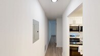 Located at 39 Broad Street Ext, Unit 206 in Groton, Connecticut, this two-story residence offers two bedrooms, one bathroom, and a thoughtfully arranged layout spread across two floors. The main living level features light hardwood-style flooring and is anchored by a well-appointed galley kitchen with white shaker cabinetry, granite-style countertops, stainless steel appliances including a range, microwave, dishwasher, and refrigerator. A ceiling fan and natural light from a window overlooking greenery add to the kitchen's welcoming atmosphere. The upper floor, which comprises the majority of the home's total footprint, is accessed via a staircase with a classic white banister railing. A hallway connects to the two bedrooms, both finished with plush carpet and windows with blinds that invite natural light. The primary bedroom includes baseboard heating and a window-mounted air conditioning unit. The bathroom features a tiled tub-shower combination with subway tile surround and brushed nickel fixtures. A private balcony off the upper hallway overlooks a lush, tree-lined landscape, providing a tranquil outdoor retreat. Two hallways provide seamless circulation throughout the home.