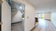 This well-appointed 2-bedroom, 2-bathroom residence in Darien, IL offers a thoughtfully designed single-floor layout with modern finishes throughout. Light wood-tone flooring flows seamlessly across the open-concept kitchen and living area, creating a bright and cohesive atmosphere. The kitchen is a standout feature, boasting warm wood cabinetry, quartz countertops with a subtle veining pattern, a curved center island with an undermount sink, stainless steel appliances, a subway tile backsplash, and elegant pendant lighting. The living area benefits from a sliding glass door that invites natural light and provides outdoor views of lush greenery. Both bedrooms feature light hardwood floors, neutral walls, and sliding glass door or window access to natural light; the primary bedroom includes a dedicated closet. The two bathrooms are finished with marble-style tile on floors and walls — one features a walk-in glass-enclosed shower, while the other offers a full tub-shower combination, both with wood-toned vanities and backlit mirrors. A dedicated laundry room houses a full-size washer and dryer. The home combines clean, contemporary design with practical amenities for comfortable everyday living.
