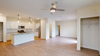 Located at 5214 Browning Ln in Leland, NC, this two-story home offers a well-designed layout across two levels. The ground floor houses an attached garage with a clean concrete floor and interior access door, while the main living areas occupy the upper level. The open-concept kitchen and living room create a bright, airy atmosphere, highlighted by light wood-look flooring, recessed lighting, and a ceiling fan. The kitchen is outfitted with white shaker-style cabinetry, granite countertops, subway tile backsplash, stainless steel appliances including a refrigerator, and a built-in wine rack accent above. A separate living room provides additional gathering space, also featuring a ceiling fan and natural light from a large window with exterior views. The generously sized primary bedroom offers its own ceiling fan, a large window that fills the room with natural light, and direct access to both a walk-in closet with wire shelving and a standard closet. The full bathroom includes a soaking tub and shower combination, white vanity cabinetry with a mosaic tile backsplash, and wood-look flooring that carries a cohesive warmth throughout the home. Clean, neutral tones and modern hardware complete the polished, move-in-ready feel of this Leland residence.