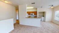 This 3-bedroom, 2-bathroom home is designed with functional living in mind. The layout, visible in the floor plan, reveals a well-organized single level accessed by a carpeted staircase with a handrail, leading to the main living areas. The open-concept kitchen features warm honey-toned cabinetry, granite-style countertops, and white appliances including a range, microwave, and refrigerator. A peninsula counter separates the kitchen from the carpeted living area, creating a natural flow between spaces. Conveniently tucked just off the kitchen is an in-unit laundry closet housing a full-size washer and dryer.

The three bedrooms are carpeted and bathed in natural light through large windows with outdoor views. The primary bedroom connects directly to a full bathroom, while a spacious walk-in closet with wire shelving provides generous storage. Both bathrooms are finished consistently, featuring tile flooring, wood-toned vanities with stone-style countertops, large mirrors, and a tub-shower combination. The neutral color palette and clean finishes throughout give the home a bright, move-in-ready appearance.