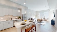 Located at 2008–2032 N Beauregard St in Alexandria, Virginia, this single-floor residence offers a thoughtfully designed open-concept layout with clean, contemporary finishes throughout. Light wood-style flooring runs continuously across the living areas, enhancing the sense of cohesion and space.

The kitchen is a standout feature, equipped with stainless steel appliances — including a refrigerator, range, microwave, and dishwasher — complemented by white shaker cabinetry extending to the ceiling for generous storage. A white quartz peninsula with bar seating serves as both a dining and gathering space, while globe pendant lights add a refined touch. A subway tile backsplash completes the polished aesthetic.

The open living area receives substantial natural light through large windows and flows seamlessly from the kitchen, creating an airy, connected atmosphere. Elevated ceilings contribute to the spacious feel of the main living zone.

The bedrooms are well-proportioned and bright, each featuring windows with outdoor views of surrounding greenery. Neutral wall tones and wood flooring maintain a consistent, calm palette.

The bathroom includes a tiled tub-shower combination, a white vanity with quartz countertop, and wood-look flooring, offering a clean and functional design. Overall, the residence presents a modern, light-filled environment well-suited to comfortable everyday living.