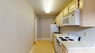 Located at 32 High St in New Haven, CT, this one-bedroom, one-bathroom unit offers a practical and well-organized single-floor layout. The living area features warm hardwood flooring and large gridded windows that allow natural light to fill the space, creating an inviting atmosphere. A dedicated HVAC unit provides climate control, and clean gray-toned walls offer a neutral backdrop throughout.

The galley-style kitchen is efficiently designed with light wood cabinetry both above and below the countertops, providing ample storage. It is equipped with a four-burner electric coil range, an over-the-range microwave, a refrigerator, and a dishwasher, all in white. Light tile flooring completes the kitchen's clean, functional aesthetic. A window at the end of the kitchen brings in additional natural light.

The bedroom features beautiful hardwood flooring and includes a spacious closet with double doors and built-in shelving, offering generous storage. The full bathroom is finished with classic small-format white mosaic tile flooring and includes a single-sink vanity with light wood cabinetry, a toilet, and a full bathtub with shower. A frosted window above the tub provides natural light while maintaining privacy. This unit offers a straightforward, comfortable layout in a convenient New Haven location.