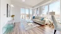 Located at 40 Kirkland Private in Ottawa, this well-designed 2-bedroom, 1-bathroom unit offers a bright and modern living experience across a single floor. The open-concept kitchen and living area serves as the heart of the home, where large floor-to-ceiling windows and a sliding glass door flood the space with abundant natural light and provide views of the surrounding greenery. The living room features warm hardwood-style flooring and a clean, airy atmosphere. The kitchen is appointed with white cabinetry, a mix of two-tone wood upper cabinets, stainless steel appliances including a full-size refrigerator and range, light tile flooring, and a sleek white kitchen island with pendant lighting overhead — ideal for both cooking and casual dining. Both bedrooms are comfortably sized, featuring hardwood-style flooring, built-in sliding door closets, and windows that bring in natural light. The primary bedroom offers a calm, functional retreat. The bathroom is finished with large-format tile on both the floors and walls, and includes a soaking tub with a shower. A hallway connects the bedrooms and provides a smooth flow throughout the unit. The overall design is contemporary and cohesive, with a neutral white palette that enhances the sense of space and light.