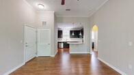 Located in Jacksonville, FL (32218), this 2-bedroom, 1-bathroom single-floor residence offers a well-designed layout with thoughtful finishes throughout. Rich hardwood-style flooring runs through the main living areas, complemented by crown molding and neutral-toned walls that create a clean, cohesive aesthetic.

The open living room is bright and airy, featuring a ceiling fan, large windows with blinds that invite natural light and outdoor views of surrounding greenery. Crown molding adds a refined architectural touch to the space.

The kitchen is a standout feature, showcasing dark espresso cabinetry, granite countertops, stainless steel appliances, and a curved breakfast bar with pendant lighting overhead. A track light fixture and a window above the sink enhance both functionality and ambiance. An arched pass-through connects the kitchen to the hallway, adding architectural character.

Both bedrooms are comfortable and well-lit. The primary bedroom includes plush carpeting, a ceiling fan, a walk-in closet, and direct access to the bathroom. The second bedroom also features carpeting and windows with blinds.

The bathroom is finished with tile-surround tub/shower, granite vanity countertop, and wood-style flooring. A dedicated closet with built-in shelving adds convenient storage. Crown molding and consistent finishes tie the entire residence together cohesively.