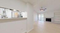 Located in Mesquite, TX, this single-floor, 2-bedroom, 2-bathroom residence offers a clean, modern aesthetic with a thoughtfully designed open layout. The living room serves as the heart of the home, featuring vaulted ceilings, light wood-style flooring, a ceiling fan, and a tile-surround fireplace flanked by a built-in bookshelf. Large sliding glass doors flood the space with natural light and provide outdoor views. The kitchen is efficiently designed with gray cabinetry, white countertops, a subway tile backsplash, stainless steel appliances including a range and dishwasher, and a double-basin sink. A pass-through window connects the kitchen to the adjoining dining area, enhancing the open feel. Both bedrooms are carpeted and feature ceiling fans and windows with outdoor tree views, creating a comfortable and serene atmosphere. The bathrooms are finished with large-format gray tile surrounds in the tub-shower combinations, white vanities, and light flooring. Additional highlights include multiple closets for storage, a dedicated laundry area with hookups, and a hallway connecting the private quarters to the main living spaces. The overall palette of bright whites and light neutrals gives the home a fresh, move-in-ready appeal.