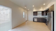 This well-appointed two-story residence offers a thoughtfully designed layout spread across two levels. The main floor features an open-concept living and kitchen area finished with light hardwood flooring that enhances the bright, airy atmosphere. The kitchen is equipped with dark wood cabinetry, granite countertops, and a full suite of stainless steel appliances including a refrigerator, range, microwave, and dishwasher. Recessed lighting illuminates the space, while large windows allow natural light to flow freely throughout. A staircase connects the main level to the upper floor, where plush carpeted bedrooms provide a comfortable retreat. One bedroom features a vaulted ceiling and a generous window with neighborhood views, adding architectural character and openness. Additional bedrooms are similarly well-lit with large windows and neutral tones. The upper floor also includes a spacious walk-in closet outfitted with multiple hanging rods and shelving for ample storage. Bathrooms are finished with granite-topped dark wood vanities, tub-shower combinations, and light hardwood-style flooring, maintaining a consistent, modern aesthetic throughout. Clean lines, neutral color palettes, and quality finishes define the overall character of this move-in-ready home.