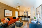 This single-story residence at 27665 Forbes Rd in Laguna Niguel, California, showcases a cohesive and well-appointed interior design throughout its thoughtfully arranged layout. The living room serves as a welcoming focal point, featuring wood-look flooring, a statement chandelier, a textured accent wall, and a French door that invites natural light and outdoor greenery into the space.

The kitchen is a standout area, combining navy blue lower cabinets with crisp white upper cabinetry, white quartz countertops, a classic subway tile backsplash, and stainless steel appliances including a gas range and French door refrigerator. A pendant light adds a warm finishing touch. The adjacent dining area features a bold grasscloth-textured accent wall, wood-look flooring, and room for intimate gatherings.

Each bedroom offers distinct character: one highlights a grasscloth feature wall with vaulted ceiling and walk-in closet, while another showcases a bold blue patterned accent wall paired with an ornate chandelier and its own walk-in closet. Both bathrooms are finished with navy vanities, subway tile, wood-look tile flooring, and built-in shelving — one featuring a glass-enclosed walk-in shower, the other a full tub-shower combination.