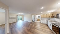 Located on Lakeland Drive NE in Willmar, Minnesota, this 2-bedroom, 1-bathroom residence offers a thoughtfully designed single-floor layout with a clean, modern aesthetic throughout. Warm hardwood-style flooring flows seamlessly across the open-concept living room and kitchen area, creating a cohesive and inviting atmosphere. The living room is bathed in natural light from a sliding glass door that opens to a private balcony overlooking lush greenery, providing a pleasant outdoor retreat.

The kitchen is well-equipped with stainless steel appliances — including a refrigerator, electric range, microwave, and dishwasher — complemented by two-tone cabinetry featuring natural wood uppers and crisp white lowers, a herringbone-patterned tile backsplash, and stone-look countertops that add a contemporary touch.

Both bedrooms continue the hardwood-style flooring and are finished with neutral tones, offering a calm and versatile space. Each room features windows with views of the surrounding greenery, and at least one bedroom includes a built-in closet with hanging storage. The full bathroom is clean and functional, featuring a tub/shower combination with bright white surround. The overall ambiance is fresh, bright, and move-in ready.