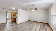This single-floor, one-bedroom, one-bathroom residence offers a thoughtfully organized layout that maximizes functionality within a compact footprint. The open-concept main area seamlessly combines the living room, dining room, and kitchen, creating a bright and cohesive space. Durable wood-look laminate flooring runs throughout the main living areas, complemented by vaulted ceilings that lend a sense of openness and volume. A ceiling fan with integrated lighting serves as a practical focal point in the living area.

The galley-style kitchen is efficiently designed with warm honey-toned wood cabinetry on both walls, light countertops, a double sink, and white appliances including an electric range and refrigerator. A pantry provides additional storage and enhances the kitchen's organization.

The bedroom is a comfortable, well-proportioned retreat featuring plush carpet flooring, a ceiling fan, a window allowing natural light, and direct access to a closet. The full bathroom includes a tub/shower combination, a toilet, and a wood-vanity with a single sink, all set on richly toned tile flooring. The overall design is clean and neutral throughout, offering a functional and livable environment.