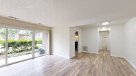 Located at 2018 Cunningham Dr in Hampton, VA, this well-designed one-bedroom, one-bathroom residence offers a comfortable and functional single-floor layout. The open living and dining area is bright and welcoming, featuring light hardwood-style flooring, neutral toned walls, and a textured ceiling. Large sliding glass doors flood the space with natural light and provide a pleasant view of the surrounding greenery, creating an airy and connected indoor-outdoor feel. A separate entry area with matching flooring adds a practical transition into the main living space.

The kitchen is efficiently designed with rich dark wood cabinetry, striking granite countertops, stainless steel appliances including a refrigerator and dishwasher, and a window that brings in additional natural light. The layout maximizes storage and workspace within a compact footprint.

The generously sized bedroom features plush wall-to-wall carpeting, a bright window with blinds, and access to multiple closets, including a spacious walk-in closet with built-in shelving — offering exceptional storage for the space.

The bathroom is thoughtfully finished with white subway tile surrounding a full soaking tub and shower combination, accented by a decorative mosaic tile border. A dark wood vanity with a granite countertop and a round mirror complete the polished look. An in-unit laundry area adds everyday convenience.