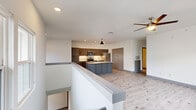 Located in Jenks, Oklahoma, this two-story residence offers a thoughtfully designed layout spread across two levels. The ground floor houses a spacious attached garage with a motorized door opener, concrete flooring, and recessed lighting — providing ample room for parking and storage.

The main living level occupies the upper floor and features light-toned hardwood-style flooring throughout, crisp white walls, and ceiling fans in both the living area and bedroom. The open-concept kitchen is a standout feature, showcasing a large center island with a granite countertop and stainless steel sink, gray shaker-style cabinetry, a white hexagonal tile backsplash, and a full suite of stainless steel appliances including a refrigerator, range, and microwave. A pendant light anchors the island, adding a modern touch.

The living area is bright and airy, with a bank of windows inviting natural light and views of the surrounding neighborhood. The bedroom is generously sized, offering dual windows with natural light and a ceiling fan, and is finished with the same light hardwood-style flooring. The bathroom features large-format tile flooring, gray shaker vanity cabinets, granite countertops, a wide mirror with overhead lighting, and a tiled walk-in shower. A staircase connects both floors, completing this clean, contemporary home.