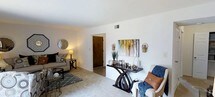 This 2-bedroom, 1-bathroom residence is thoughtfully designed across a single floor, offering a practical and comfortable layout. The living area serves as the heart of the home, featuring neutral wall-to-wall carpeting that adds warmth underfoot, and crisp white walls that create a bright, clean backdrop throughout. The space is generously proportioned, providing ample room for both lounging and entertaining. A central hallway connects the living area to the private quarters, ensuring a smooth and functional flow throughout the unit. The living room benefits from well-placed accent lighting and features a decorative wall display area, lending a polished, curated feel to the space. Smooth white ceilings and a neutral color palette keep the interiors feeling open and airy, while a HVAC vent ensures year-round climate comfort. The overall ambiance is welcoming and move-in ready, with clean lines and a versatile design that easily accommodates a variety of furnishing styles. This residence strikes a balance between practicality and comfort, making it an ideal home for those seeking a well-organized, single-level living experience.