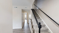 Located at 25 Bainbridge Ave in Hampton, Virginia, this two-story home offers a practical and well-organized layout spread across two floors. The main level features a bright living room with hardwood-style flooring, large windows, and a glass-panel entry door that invites abundant natural light. The kitchen is efficiently designed with white cabinetry, white subway tile backsplash, stainless steel appliances including a refrigerator and range, and wood-look flooring. A pantry with louvered doors provides convenient storage, and a dedicated dining area completes the main living space. A full bathroom on the lower level features a tub-shower combination, wood-look flooring, and white vanity with clean finishes. A carpeted staircase with a classic black and white balustrade leads to the upper level. Upstairs, two carpeted bedrooms offer a comfortable retreat, each with natural light from windows. The generously sized primary bedroom includes a double-door closet and additional storage access. The second full bathroom mirrors the clean aesthetic of the first, featuring a tub-shower combo, white vanity, and matte black hardware accents. With five total closets throughout, this home provides exceptional storage for its size.