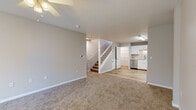 Located at 1507 Timber Creek Dr in Columbia, Missouri, this two-story home offers a thoughtfully designed layout with a clean, modern aesthetic throughout. The main level features an open living area finished with soft, neutral-toned carpet and a ceiling fan, flowing seamlessly into a well-appointed kitchen. The kitchen is a standout feature, showcasing white shaker-style cabinetry, light stone countertops, a skylight that invites natural light, and a full suite of stainless steel appliances including a refrigerator, range, microwave, and dishwasher. Light wood-look flooring ties the kitchen and adjoining areas together. A staircase with white balusters connects the two floors, and additional storage is accessible near the kitchen entry. The upper level hosts multiple carpeted bedrooms, each equipped with ceiling fans and ample space. The bedrooms are finished in soft neutral tones, lending a calm and versatile atmosphere. Two full bathrooms serve the home, each featuring wood-look flooring, a tub-shower combination, white vanity with sink, and toilet. The consistent use of neutral colors, modern fixtures, and quality finishes throughout the home creates a cohesive and move-in-ready living environment.