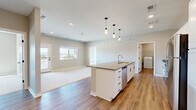 Located on Compass Dr in Grand Junction, Colorado, this well-appointed 2-bedroom, 2-bathroom single-floor residence offers a thoughtfully designed open-concept layout with clean, contemporary finishes throughout. The kitchen serves as the heart of the home, featuring a large central island with a dark quartz countertop, a undermount sink, pendant lighting, white shaker cabinetry, and a full suite of stainless steel appliances. The kitchen flows seamlessly into the living room, which is carpeted and filled with natural light, and opens directly onto a private balcony with outdoor views of the Grand Junction landscape. Both bedrooms are generously sized with plush carpet, neutral-toned walls, and dedicated closets — the primary bedroom includes an en-suite bathroom with a dual-sink vanity, white cabinetry, and wood-look flooring. The second bathroom features a single-sink vanity with matching white cabinetry and quartz countertops. A dedicated in-unit laundry area with a full-size washer and dryer provides added convenience. Black hardware accents, recessed lighting, and wood-look plank flooring in main areas tie the design together for a cohesive, modern aesthetic throughout.