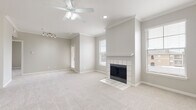 This single-floor unit offers a thoughtfully designed layout that balances comfort and functionality. The spacious living area serves as the heart of the home, anchored by a classic tile-surround fireplace with a white mantel and complemented by soft, neutral-toned carpet underfoot. Crown molding traces the ceiling, while a ceiling fan with integrated lighting adds both style and practicality. Multiple windows fitted with horizontal blinds fill the room with natural light and offer views of the surrounding exterior.

The open-concept kitchen is connected to the living space via a raised breakfast bar, creating a seamless flow ideal for entertaining. The kitchen features gray cabinetry, white appliances including a refrigerator, range, and microwave, a double basin sink with a brushed nickel faucet, and warm hardwood-style flooring. Track lighting above adds a functional accent.

The bedroom is generously sized with plush carpet and direct access to a private balcony through a sliding glass door, offering an outdoor retreat. A ceiling fan keeps the room comfortable year-round. The bathroom is appointed with a soaking tub and shower combination set against marble-style surround walls, complemented by hardwood-style flooring, built-in shelving, and clean white fixtures throughout.