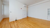 Located at 503 Longwood Ave in Bedford, Virginia, this single-floor unit offers a thoughtfully designed layout that maximizes its compact footprint. The open-plan kitchen and living area forms the heart of the space, featuring warm honey-toned hardwood floors that run throughout, crisp white walls, and elevated ceilings that lend an airy, spacious feel. A wall-mounted mini-split HVAC unit ensures year-round climate comfort.

The kitchen is well-appointed with grey shaker-style cabinetry accented by gold hardware, white countertops, and a full suite of stainless steel appliances including a range, over-the-range microwave, dishwasher, and refrigerator. A built-in glass-front cabinet adds a classic architectural detail to the kitchen wall. The living area benefits from a generous bank of windows fitted with horizontal blinds, flooding the space with natural light and providing views of the surrounding neighborhood.

The bathroom continues the clean, modern aesthetic with grey shaker vanity cabinetry, a white countertop sink, large mirror, and polished gold fixtures and hardware, lending a refined, contemporary touch. The overall design is clean and neutral throughout, creating a versatile and move-in ready space.
