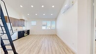 This thoughtfully designed two-level studio in Chula Vista, California, makes the most of every square foot with a clean, modern aesthetic throughout. Light wood-tone flooring runs continuously across both levels, complementing the bright white walls and creating a warm, cohesive feel.

The main level is anchored by a well-appointed kitchen and living area. The kitchen features two-tone cabinetry — warm wood-grain uppers paired with dark lower cabinets — set against sleek white quartz countertops. Full stainless steel appliances, including a refrigerator, dishwasher, and range, are neatly integrated, while a stacked washer and dryer provide added convenience. A window above the counter brings in natural light, keeping the space feeling open and airy.

The bathroom is clean and functional, outfitted with a walk-in shower featuring built-in shelving and a matte black showerhead, complemented by open dark-toned shelving for additional storage.

The upper level offers a versatile loft space bathed in natural light from a large window with exterior views, and is equipped with a wall-mounted mini-split HVAC unit for personalized climate control. The lower living area also features a mini-split unit, ensuring comfort throughout. Recessed lighting and abundant natural light from multiple windows enhance the overall brightness and livability of this efficient, move-in-ready studio.