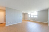Located at 1577 Lawrence Ave W in Toronto's Lawrence Heights neighbourhood, this one-bedroom, one-bathroom unit offers a thoughtfully laid-out single-floor living space. Light wood laminate flooring runs consistently throughout, providing a warm and cohesive feel across all rooms.

The galley-style kitchen is efficiently designed, featuring white cabinetry on both sides, a double stainless steel sink with grey countertops, a tiled backsplash, and stainless steel appliances including a refrigerator and electric range. The kitchen opens toward the hallway, creating a sense of connectivity throughout the unit.

The living room is generously sized and filled with natural light from large windows that offer views of the surrounding neighbourhood. The open layout provides ample flexibility for furniture arrangement. The bedroom is a comfortable size, also benefiting from a large window that brings in natural light and outdoor views.

The bathroom is clean and functional, featuring a full-sized soaker tub with an overhead shower, white subway tile surround, and classic chrome fixtures. A built-in niche in one area of the unit provides additional storage potential. Neutral grey walls throughout the unit complement the light flooring and create a bright, modern, and move-in-ready atmosphere.