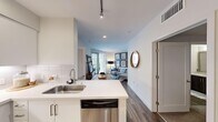 This thoughtfully designed residence offers three bedrooms and two full bathrooms across a single floor, making efficient use of its compact footprint. The open-concept kitchen and living area serves as the heart of the home, with the kitchen showcasing crisp white cabinetry, quartz countertops, a classic subway tile backsplash, and a full suite of stainless steel appliances including a gas range, over-the-range microwave, and French door refrigerator. A peninsula with an undermount sink provides additional prep space and a natural division between the kitchen and living area. The living room is bright and welcoming, featuring wood-look plank flooring, recessed lighting, and access to a patio door that invites natural light. The primary bedroom offers a comfortable, carpeted retreat, while the additional bedrooms are well-sized with ample natural light from large windows. Both bathrooms are finished with dark wood-toned vanities, white quartz countertops, and wood-look tile flooring. One bathroom features a full soaking tub with tiled surround and built-in niche. The residence is unified by a clean, modern aesthetic with neutral tones and consistent finishes throughout.