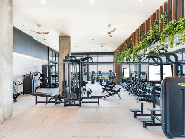 Manténgase activo en el amplio gimnasio de Modera St. Paul, que ofrece equipos de última generación y vistas inspiradoras del centro de Dallas. - Modera St. Paul