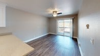 Located at 22432 Center St in Castro Valley, CA, this single-floor unit offers a well-designed, updated interior with a cohesive neutral color palette and a mix of hard and soft flooring throughout. The open-concept living and dining area features rich wood-look laminate flooring, a ceiling fan with light fixture, and a sliding glass door that opens to a private balcony, allowing generous natural light to fill the space. The kitchen is thoughtfully appointed with white shaker-style cabinetry, light stone-finish countertops, stainless steel appliances including a refrigerator, electric range, microwave, and dishwasher, and a breakfast bar peninsula that connects seamlessly to the main living area. An in-unit laundry area with a stacked washer and dryer adds everyday convenience. The bedroom is carpeted for comfort, includes a ceiling fan, a baseboard heater, and a window with an exterior view. The full bathroom features a white vanity with stone-top counters, a large wall mirror, recessed lighting, wood-look flooring, and a shower-tub combination. Recessed lighting and warm-toned walls carry throughout the hallway and common areas, giving the unit a clean, modern feel.