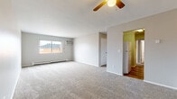 This single-floor, 3-bedroom, 1-bathroom unit offers a practical and functional layout designed for comfortable everyday living. The spacious living area is finished with soft wall-to-wall carpeting and features a ceiling fan with integrated lighting, a wall-mounted air conditioning unit, and baseboard heating — ensuring year-round climate control. A sliding window allows natural light to filter in, offering views of the surrounding neighborhood.

The layout flows through a central hallway connecting the bedrooms, bathroom, and closet. Each bedroom is carpeted and neutrally painted in light gray tones, with windows providing natural light and baseboard heating units beneath them. The generously sized primary bedroom stands out with ample room for furnishings. A dedicated closet provides additional storage.

The kitchen features warm hardwood-style flooring, white appliances including a full-size refrigerator, and is accented with green-painted walls for a touch of character. The bathroom is equipped with a full tub and shower combination, finished with classic beige square wall tiles and chrome fixtures.

Throughout the unit, clean white trim, neutral gray walls, and consistent flooring choices create a cohesive and move-in ready atmosphere suited for a variety of lifestyles.