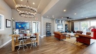 Located at 90 Molina Way in Saint Peters, Missouri, this single-floor community amenity space offers a thoughtfully designed layout that blends comfort, functionality, and modern style.

The entrance welcomes visitors with warm hardwood-style flooring, neutral gray walls, and a striking round chandelier that casts an elegant glow over the space. A high-top dining table with bar stools provides a casual gathering spot, while a large feature wall displays an eye-catching informational display, adding a sense of purpose and community to the area.

The combined living and dining room is a standout area, anchored by a built-in media wall featuring a large flat-screen TV, floating shelves adorned with candles, and a trio of framed moon-phase art pieces above. A tufted leather armchair and an industrial-style shelving unit add character, while large sliding glass doors flood the room with natural light and offer direct views of an outdoor patio and pool area.

The exercise room is vibrant and energetic, with bold orange accent walls and patterned carpet flooring. It is well-equipped with cardio machines including treadmills, ellipticals, and stationary bikes, as well as a cable machine, a dumbbell rack, and stability balls. A ceiling fan, recessed lighting, and a sliding glass door to the outdoor patio keep the space comfortable and airy.