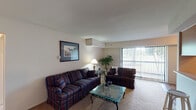 This single-floor residence offers a thoughtfully laid-out living environment across several well-defined spaces. The living room serves as the heart of the home, featuring carpeted flooring, neutral walls, and large sliding glass doors dressed with vertical blinds that invite natural light and provide outdoor views. The adjacent dining area echoes this openness with its own sliding glass door, creating a seamless connection to the outdoors.

The kitchen is equipped with warm wood cabinetry, a full suite of appliances including an electric range and refrigerator, and durable tile-style flooring. A walk-in pantry with built-in shelving provides generous storage capacity.

The residence includes two bedrooms, both finished with carpet and neutral tones. The primary bedroom features a window with outdoor views and ample floor space, while the second bedroom includes a built-in closet with bifold doors. Both rooms offer a calm, restful atmosphere.

The bathroom is clean and functional, featuring a tub-shower combination, a vanity with a wide mirror, and bright overhead lighting. Throughout the home, the consistent use of neutral color palettes and natural light creates a cohesive, comfortable ambiance suitable for everyday living.
