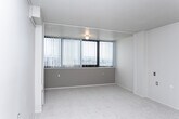 Located at 535 S 200 E in Salt Lake City, Utah, this efficient one-bedroom, one-bathroom unit offers a well-organized layout across a single floor. The space is designed to maximize functionality within a compact footprint.

A hallway entry leads into the main living area, which transitions between hardwood-style flooring and plush carpeting. The living space is served by a wall-mounted mini-split HVAC unit, providing individual climate control. A textured ceiling runs throughout the unit, adding a subtle design element.

The open kitchen area features gray cabinetry, a white refrigerator, and a range, with hardwood-style flooring that ties into the entryway. Ample storage is provided by closets visible from the hallway.

The bedroom is carpeted and features a large window fitted with vertical blinds, allowing natural light to fill the room while offering views of the surrounding Salt Lake City skyline and the Wasatch Mountains beyond.

The bathroom is cleanly appointed with white cabinetry, a stone-finish countertop with an integrated sink, a wall-mounted mirror, and a full shower-tub combo. Hardwood-style flooring continues into this space, maintaining a cohesive look throughout the unit.