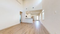This well-appointed two-story home offers 4 bedrooms and 4 bathrooms across two thoughtfully designed floors. The main level immediately impresses with a dramatic double-height ceiling in the open-concept living and dining area, where a ceiling fan, recessed lighting, and abundant natural light from multiple windows create a bright, airy atmosphere. Light wood-tone flooring flows seamlessly throughout the main level, connecting the spacious living area to the kitchen, which features white cabinetry, stainless steel appliances including a refrigerator and microwave, and a peninsula counter ideal for casual dining or meal prep. A glass door on the main floor provides direct access to the outdoors. The staircase leads to the upper level, where the bedrooms are finished with plush carpet flooring. The primary bedroom includes a generous walk-in closet with full-length hanging rods and shelving. The bathrooms are finished in a clean, modern style with white shaker cabinetry, quartz-style countertops, wood-look flooring, and tiled tub-shower combinations. A dedicated laundry room on the upper level includes a full-size washer and dryer with overhead shelving for added convenience. Throughout, the home maintains a neutral, bright palette that enhances the sense of openness and scale.