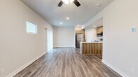 This two-story home in Kansas City, MO offers a well-designed layout across two floors, combining modern finishes with practical functionality. The main level features an open-concept kitchen and living area with wood-look luxury vinyl plank flooring, recessed lighting, and a ceiling fan. The kitchen is equipped with stainless steel appliances, including a refrigerator, range, and microwave, complemented by warm wood-toned cabinetry, a subway tile backsplash, and a peninsula with a white quartz countertop and undermount sink — ideal for both cooking and casual dining. A half bath on the main floor adds convenience for guests. The staircase, featuring dark metal balusters and carpet treads, connects to the upper level, where three bedrooms await. The spacious primary bedroom includes a ceiling fan and a dedicated bathroom with a wide vanity, white quartz countertop, and a large mirror. Secondary bedrooms are carpeted and filled with natural light from windows with outdoor views. Each bathroom carries a consistent, clean aesthetic with wood-toned cabinetry and vinyl plank flooring. The home also includes an attached garage with a concrete floor, a utility room, three closets, and a hallway that ties the upper floor together efficiently.