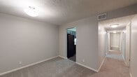 This single-floor residence offers a thoughtfully designed layout that balances functionality and comfort throughout its interconnected spaces. The kitchen is a standout feature, showcasing dark gray shaker-style cabinetry with brushed nickel hardware, light quartz countertops, a classic tile backsplash, and a full suite of black appliances including a range, over-the-range microwave, dishwasher, and refrigerator. Rich wood-look flooring grounds the kitchen and entry areas, creating a warm contrast against the neutral gray walls found throughout the unit. The living and dining areas are finished with plush carpet and textured ceilings, offering a comfortable and cohesive feel. Multiple bedrooms provide generous floor space, each carpeted and painted in soft gray tones, with windows that allow natural light to filter in. The bathrooms maintain a consistent design language, featuring gray cabinetry, quartz-style countertops, vessel sinks with brushed nickel faucets, and large mirrors. One bathroom includes a walk-in shower with tile surround, while the other features a tub. A dedicated entryway with wood-look flooring and easy access to adjoining rooms completes this well-organized, move-in-ready space.